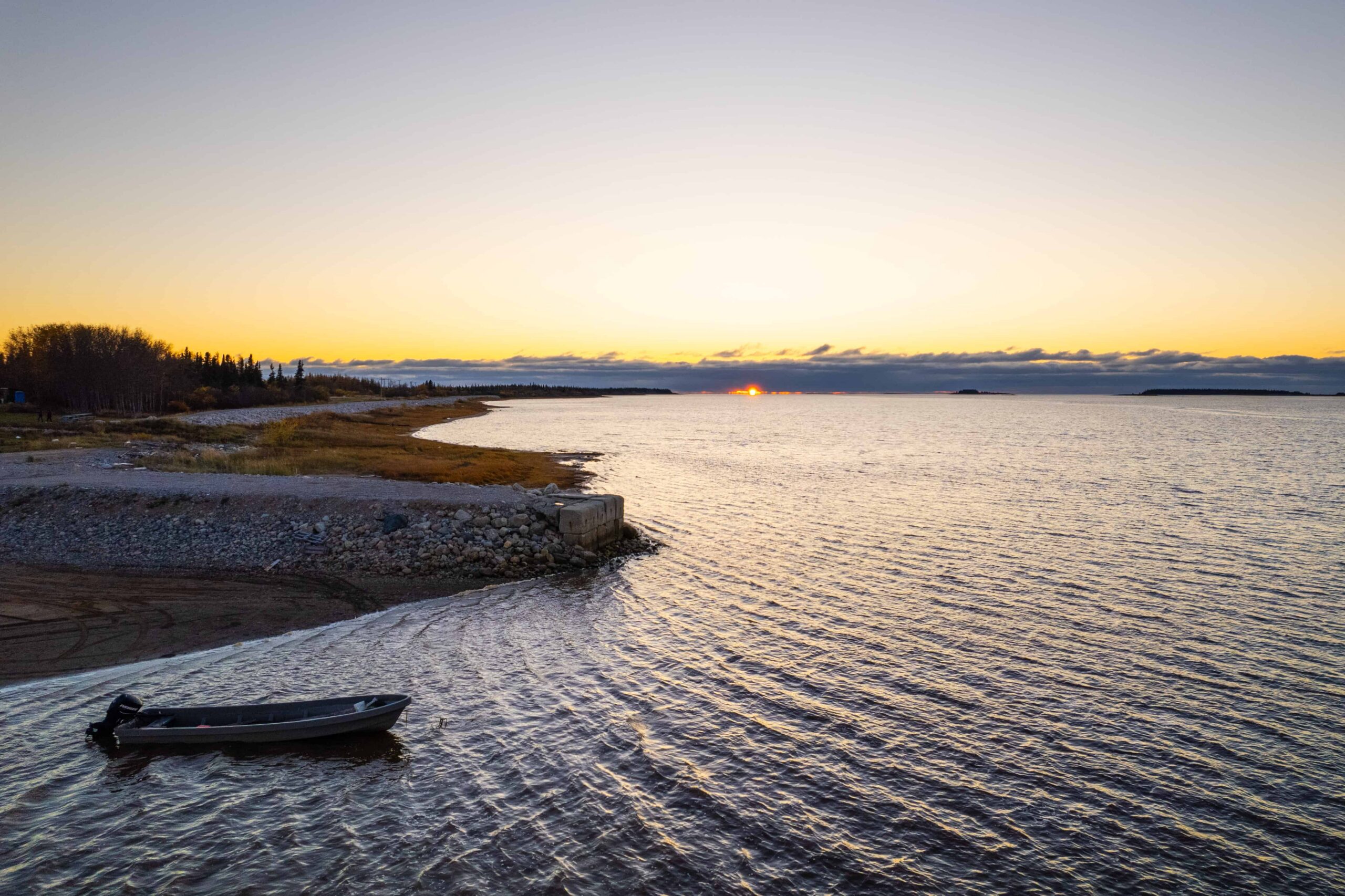 Bateau en bois près du rivage au coucher du soleil.